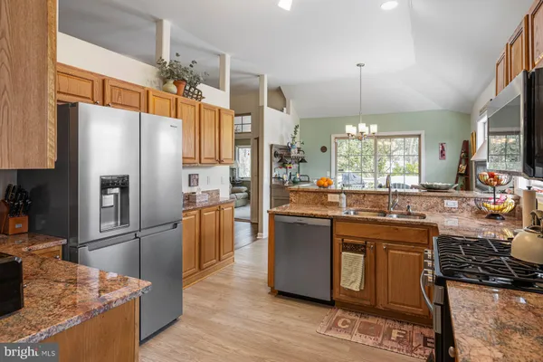 a kitchen with stainless steel appliances granite countertop a refrigerator a stove and a sink