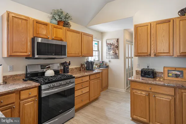 a kitchen with stainless steel appliances granite countertop a stove a sink dishwasher and a microwave oven with cabinets