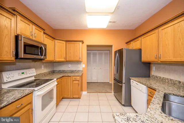 a kitchen with stainless steel appliances granite countertop a refrigerator sink and stove