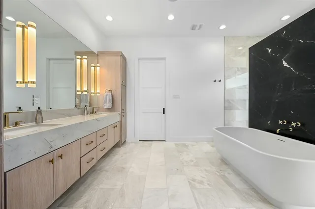 a spacious bathroom with a double vanity sink a large mirror and a bathtub