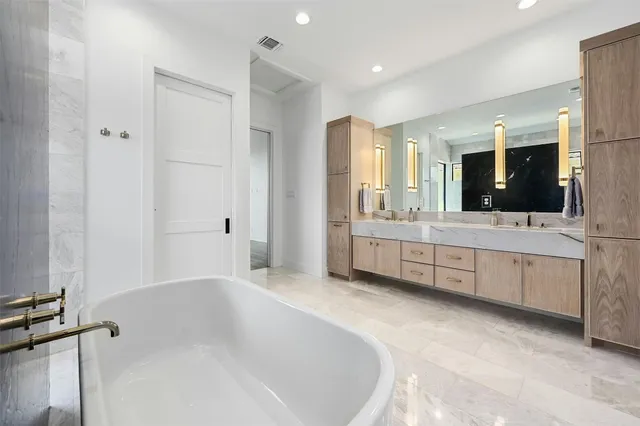 a bathroom with a double vanity sink mirror and bathtub