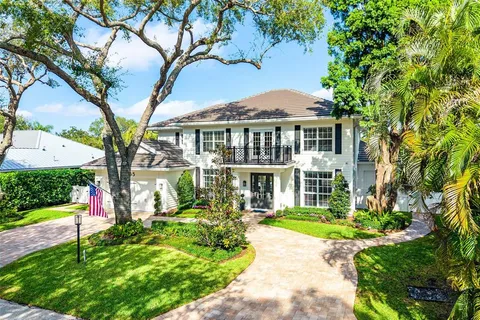 a front view of a house with a garden and trees