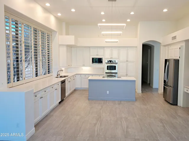 a large kitchen with stainless steel appliances kitchen island granite countertop a large counter top and stainless steel appliances