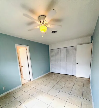 an empty room with windows and ceiling fan