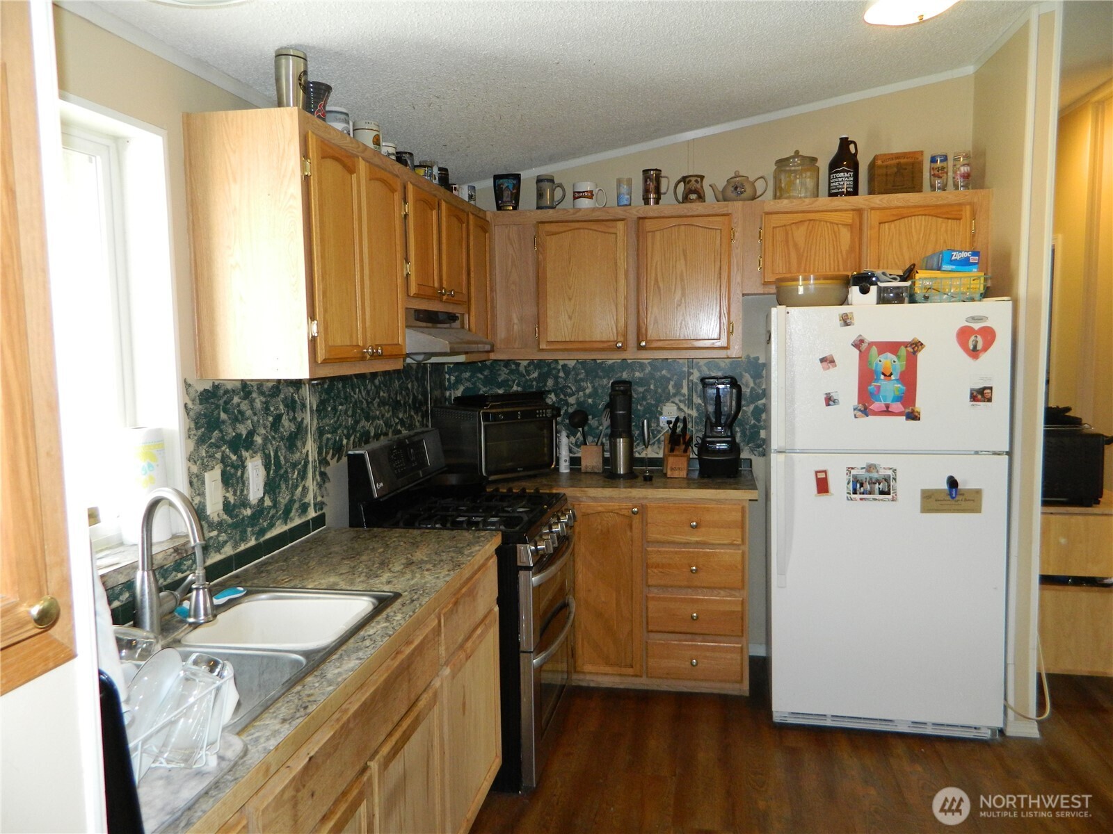28 Ridgeline Road Tonasket, WA 98855 - Photo 12 of 19 a kitchen with granite countertop a refrigerator a sink a stove and wooden floor