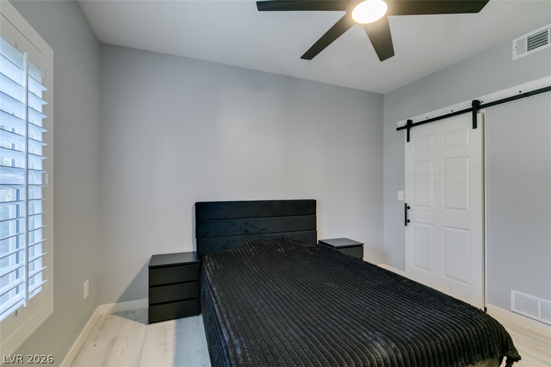 7255 West Sunset Road, Unit 1103 Las Vegas, NV 89113 - Photo 33 of 35 Comfortable bedroom with bright plank flooring and a sliding barn door for streamlined access.