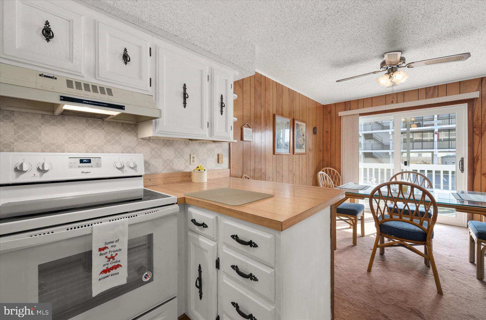 12 128th Street, Unit 2 Ocean City, MD 21842 - Photo 15 of 40 a kitchen with a stove a sink a dining table and chairs