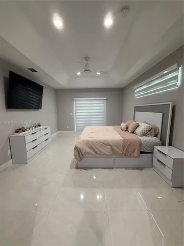 a spacious bedroom with a bed a tv and a window