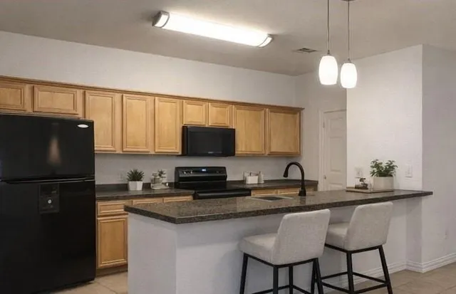 a kitchen with stainless steel appliances granite countertop a sink a stove a refrigerator a center island and cabinets