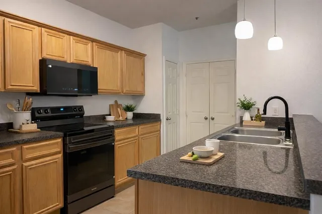 a kitchen with granite countertop a sink a stove and a microwave