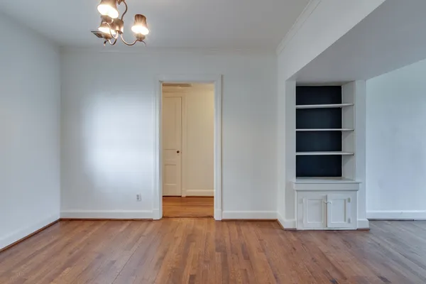 an empty room with wooden floor cabinet and windows