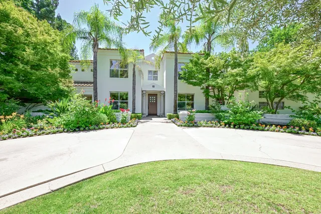 a front view of a house with lots of flowers and trees