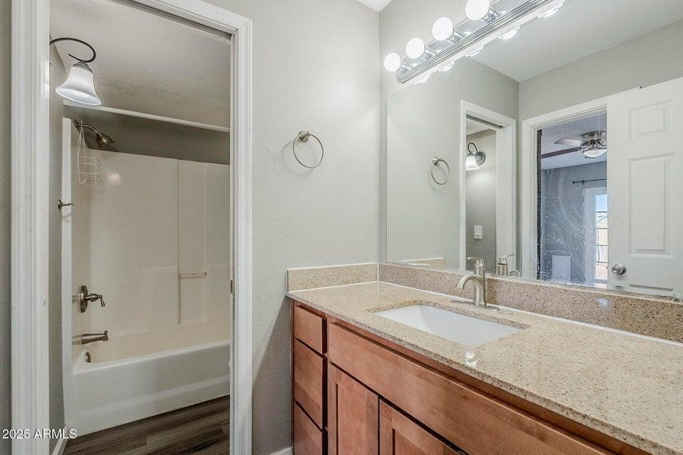 1826 N Spring, Unit 201 Mesa, AZ 85203 - Photo 11 of 17 a bathroom with a granite countertop sink a mirror and a bathtub