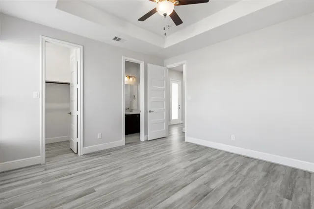an empty room with wooden floor ceiling fan and windows