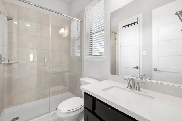 a bathroom with a granite countertop sink toilet a mirror and shower