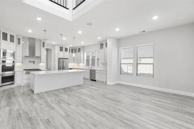 a large white kitchen with kitchen island a sink a center island stainless steel appliances and a cabinets