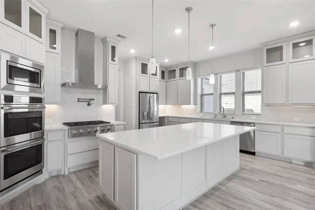 a large white kitchen with stainless steel appliances granite countertop a stove a sink dishwasher and a refrigerator