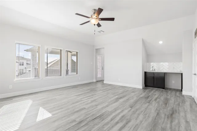 a view of an empty room with a window and wooden floor