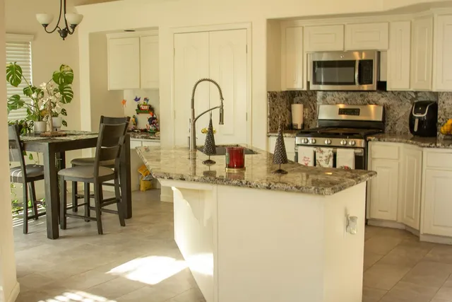 a kitchen with stainless steel appliances granite countertop a stove top oven a sink a dining table and chairs