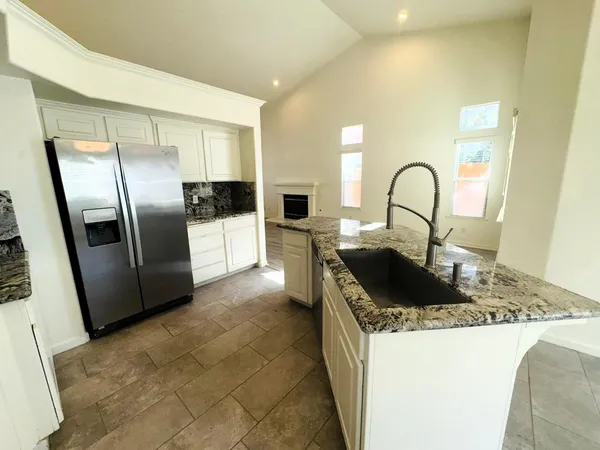 a kitchen with kitchen island a granite counter tops a sink a stove and refrigerator