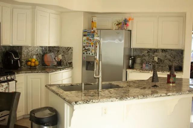a kitchen with stainless steel appliances granite countertop a sink and a refrigerator