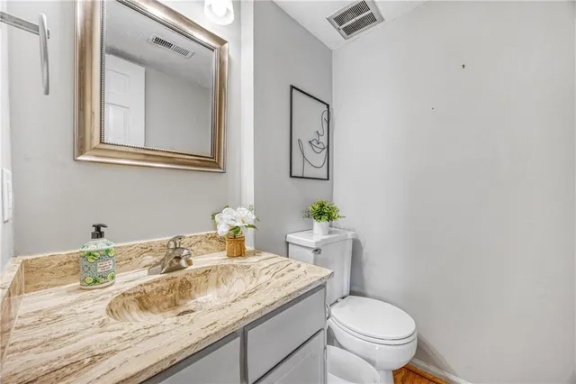 a bathroom with a granite countertop toilet sink and mirror