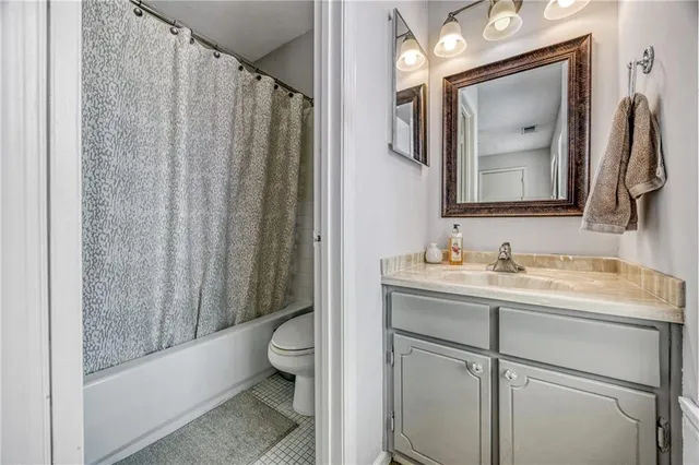 a bathroom with a granite countertop sink vanity mirror and toilet