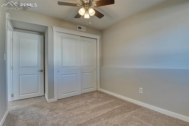 1913 Wooten Road Colorado Springs, CO 80915 - Photo 34 of 50 Unfurnished bedroom with light carpet, ceiling fan, and a closet