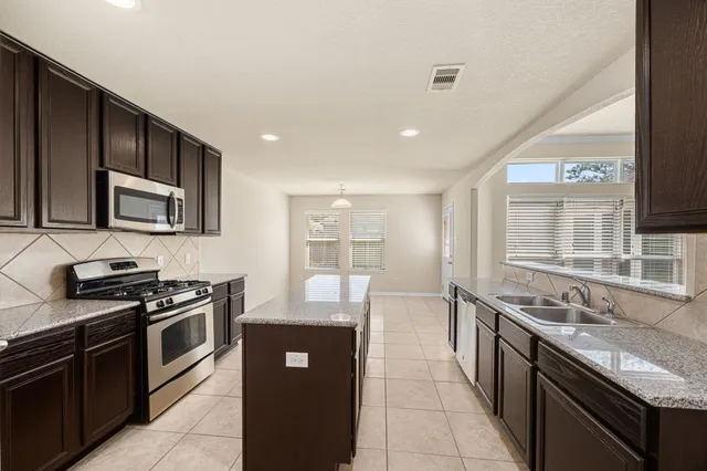 a kitchen with stainless steel appliances granite countertop a stove a sink and a microwave