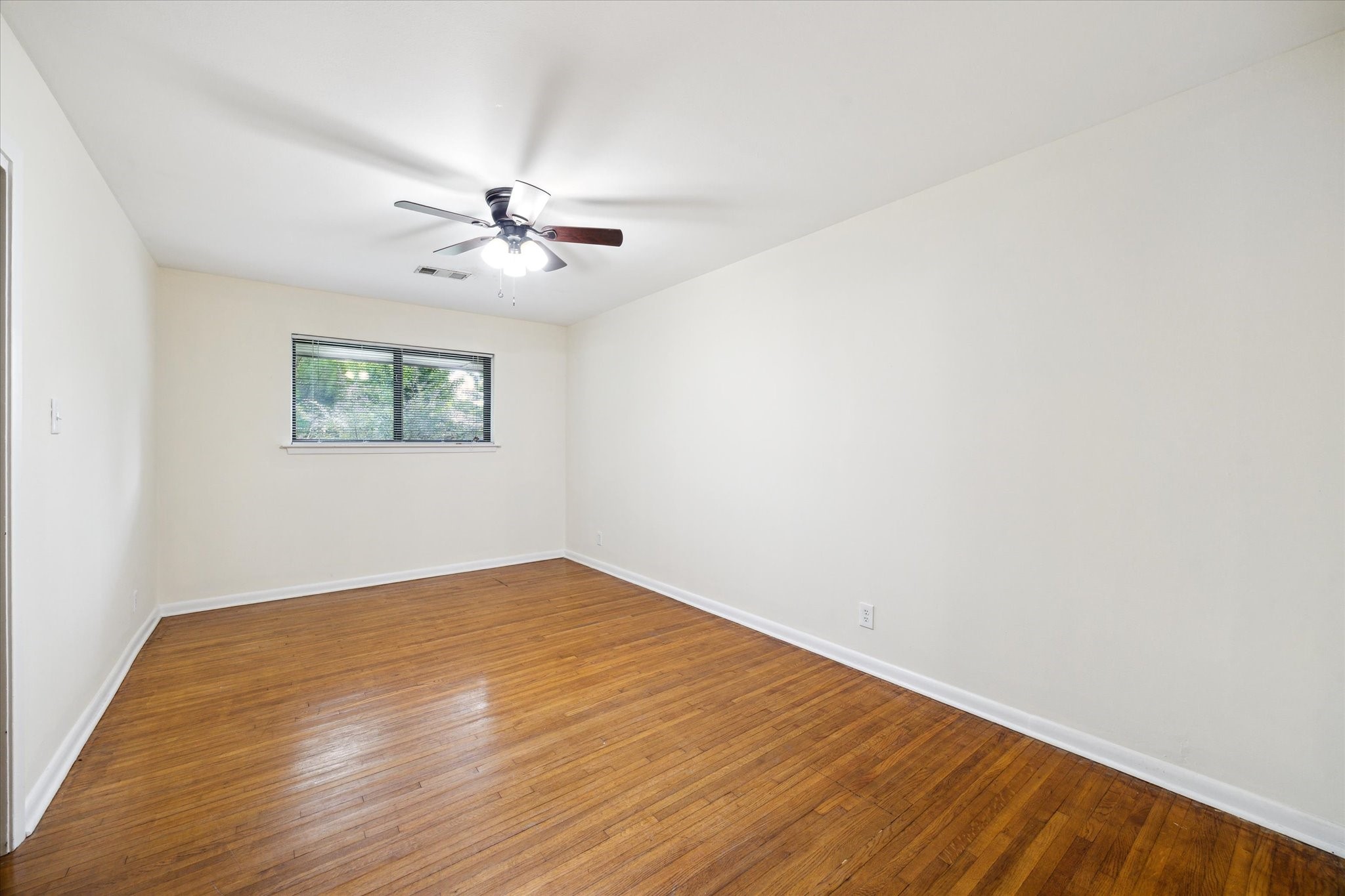 8907 Autauga Street Houston, TX 77080 - Photo 14 of 20 This room features hardwood flooring, a ceiling fan with lights, and a window providing natural light, offering a bright and inviting space.