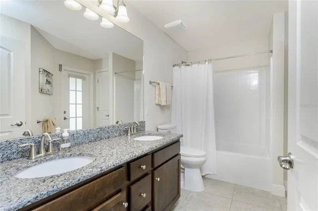 a bathroom with a granite countertop double vanity sink mirror double and shower