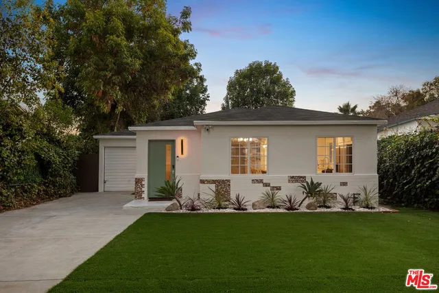 a backyard of a house with potted plants and large tree