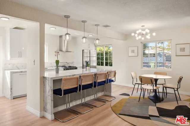 a large white kitchen with sink and chairs