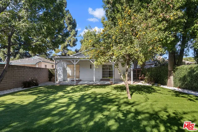a front view of a house with a garden and trees