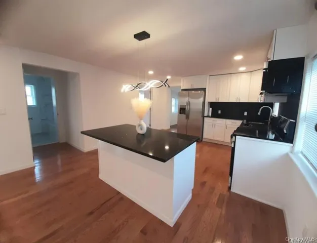 a large kitchen with stainless steel appliances kitchen island granite countertop a large counter top and a stove top oven