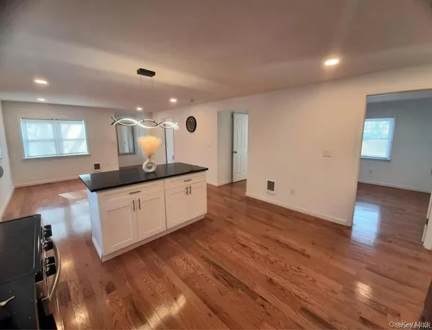 a kitchen with stainless steel appliances granite countertop a sink a stove and a wooden floors
