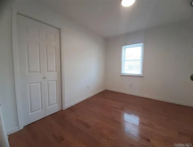 a view of an empty room and wooden floor and a window