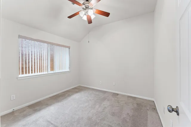 an empty room with windows and fan