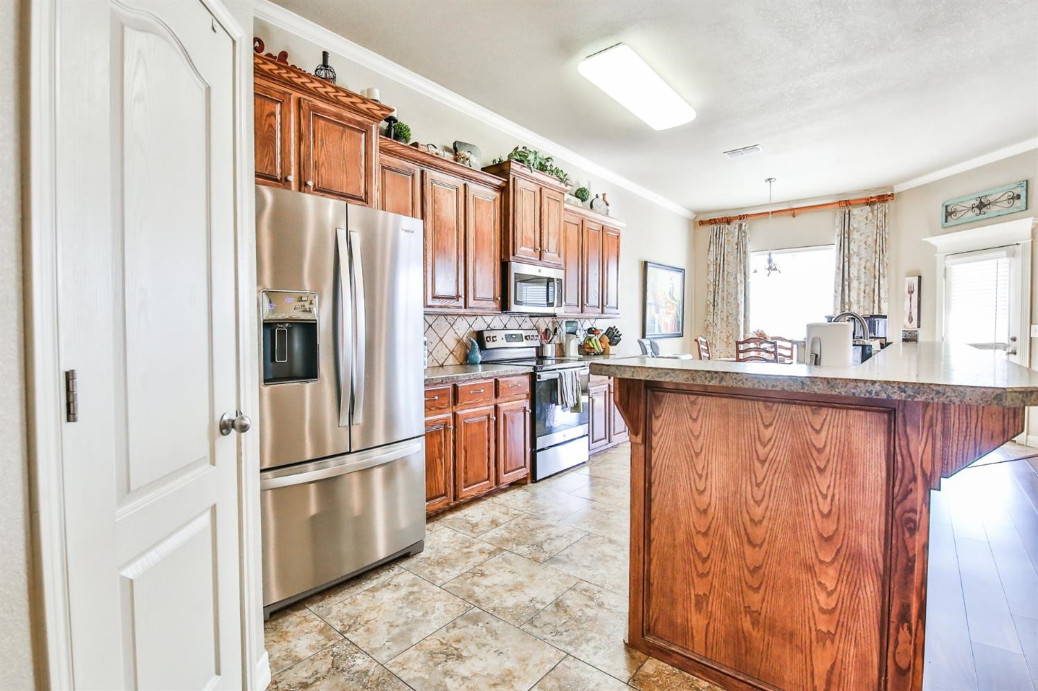6205 101st Place Lubbock, TX 79424 - Photo 11 of 37 a kitchen with stainless steel appliances granite countertop a refrigerator a sink dishwasher a stove and a dining table with wooden floor