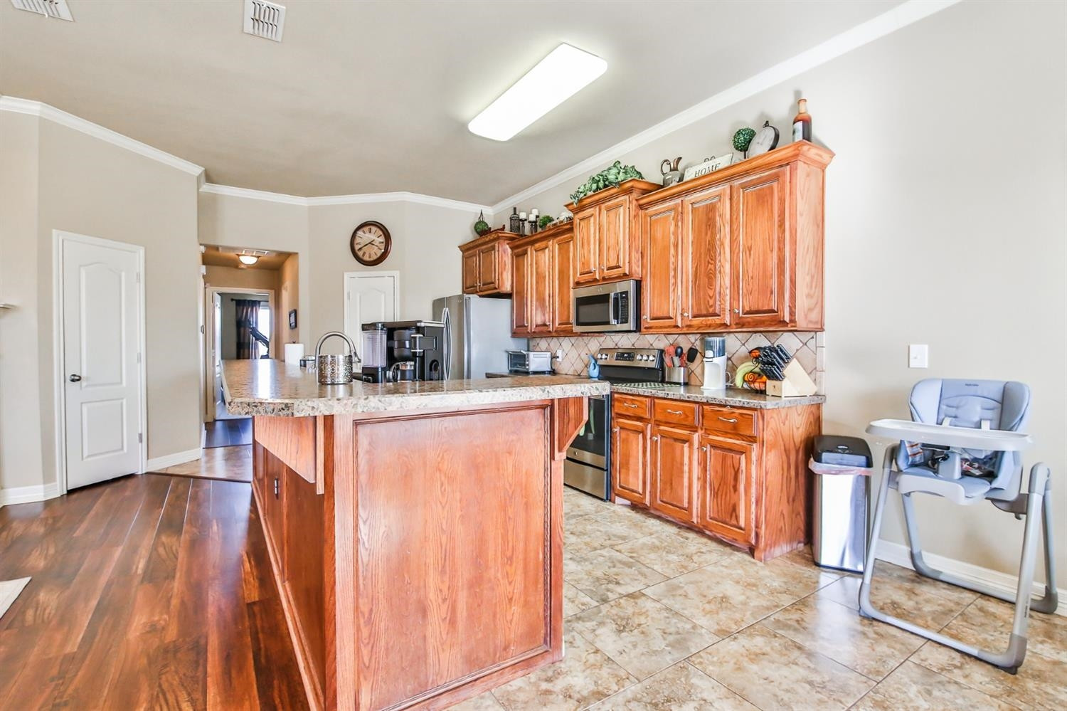 6205 101st Place Lubbock, TX 79424 - Photo 13 of 37 a large kitchen with stainless steel appliances granite countertop a stove top oven a sink dishwasher and cabinets with wooden floor