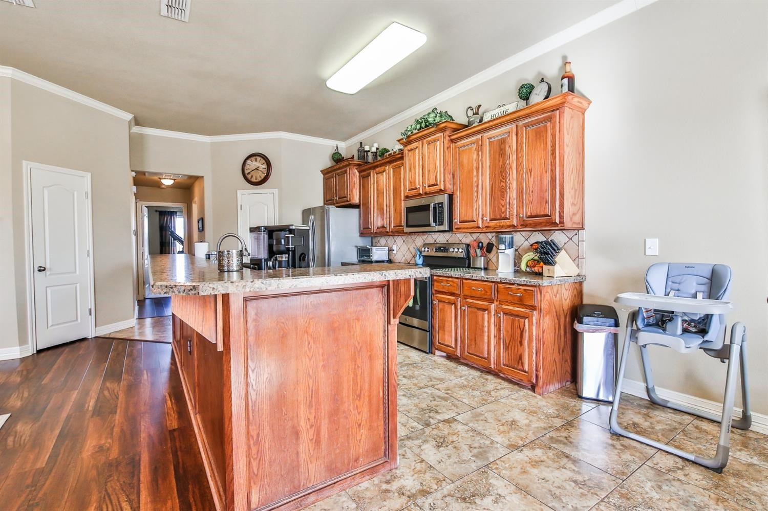6205 101st Place Lubbock, TX 79424 - Photo 14 of 37 a kitchen with stainless steel appliances granite countertop a stove top oven a sink dishwasher and a dining table with wooden floor