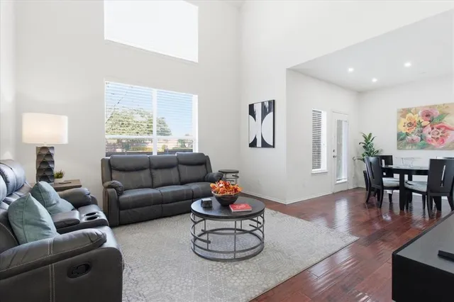 a living room with furniture a window and a dining table with wooden floor