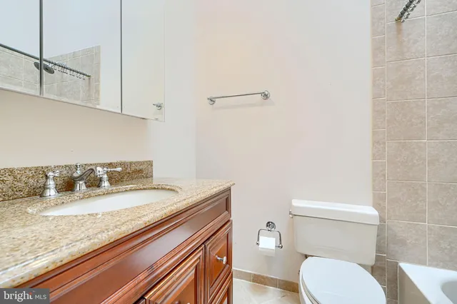 a bathroom with a granite countertop toilet sink and mirror