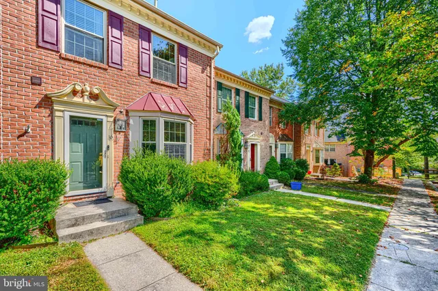 a front view of a house with garden and trees