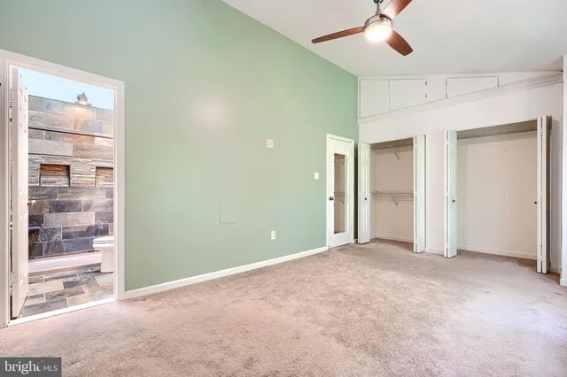 an empty room with closet and a chandelier fan