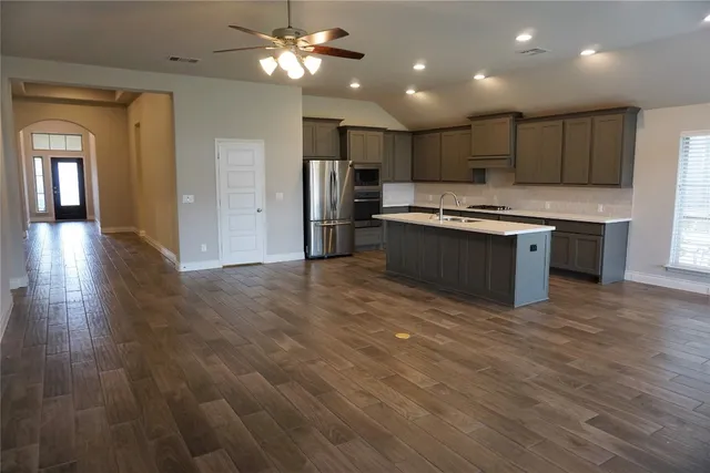 a large kitchen with stainless steel appliances granite countertop a lot of counter space and wooden floor