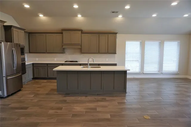 a kitchen with stainless steel appliances granite countertop a sink a stove a refrigerator and a microwave