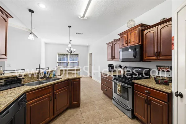 a kitchen with stainless steel appliances granite countertop a stove a sink and a microwave