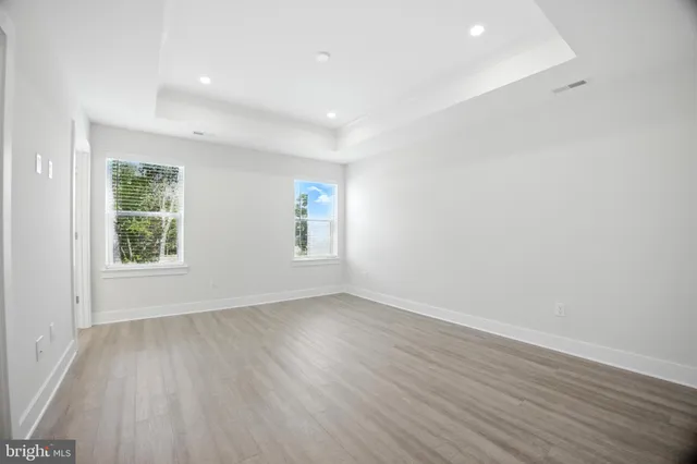 an empty room with wooden floor and windows