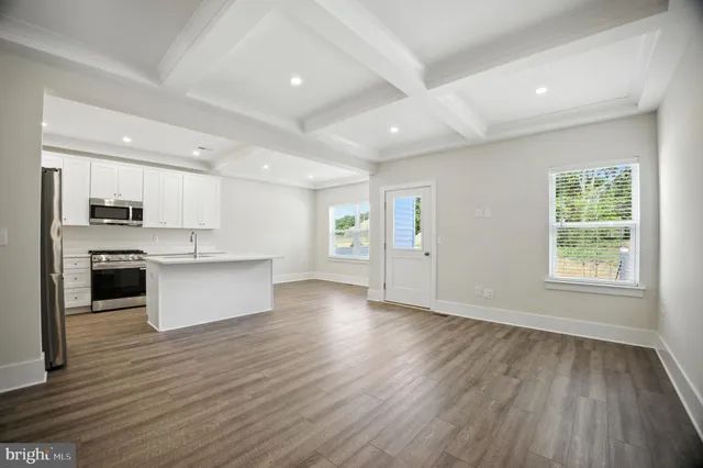 a large kitchen with stainless steel appliances granite countertop a large center island a stove a sink dishwasher and a refrigerator with wooden floor